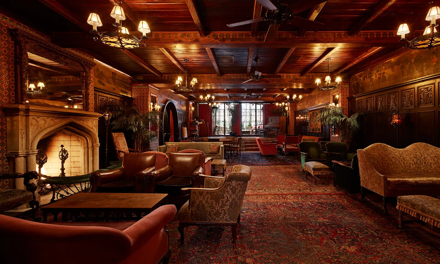 The Bowery Hotel lobby with patterned rugs, leather chairs, timber beams and a fireplace